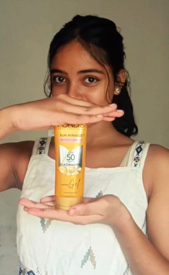 young content creator holding a skincare or beauty product while posing for a promotional photo